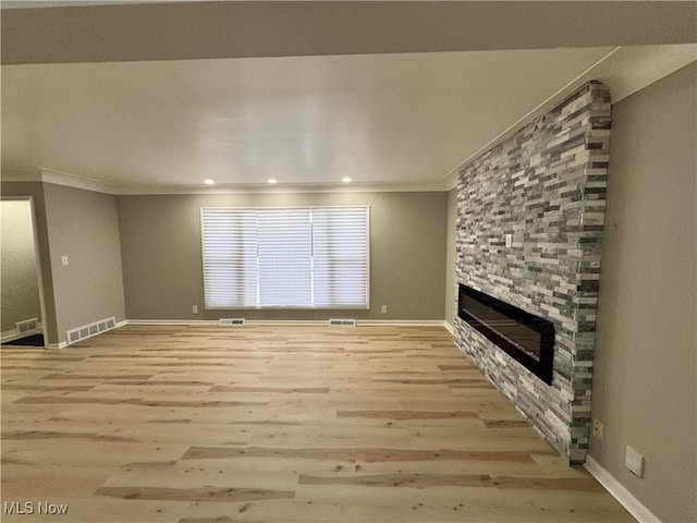 unfurnished living room with ornamental molding, a fireplace, and light hardwood / wood-style flooring