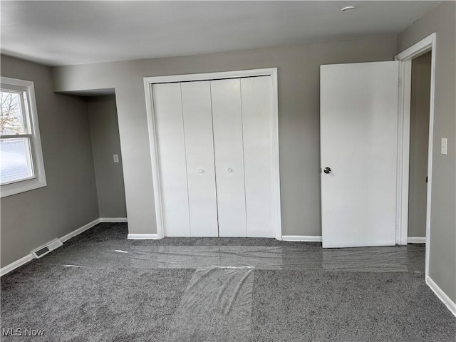 unfurnished bedroom featuring a closet and dark colored carpet