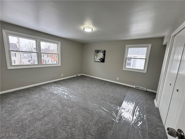 interior space with a wealth of natural light and dark colored carpet