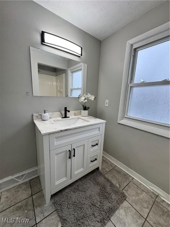 bathroom featuring a textured ceiling, tile patterned floors, and vanity