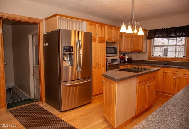 kitchen featuring decorative light fixtures, a center island, light wood-type flooring, appliances with stainless steel finishes, and a notable chandelier