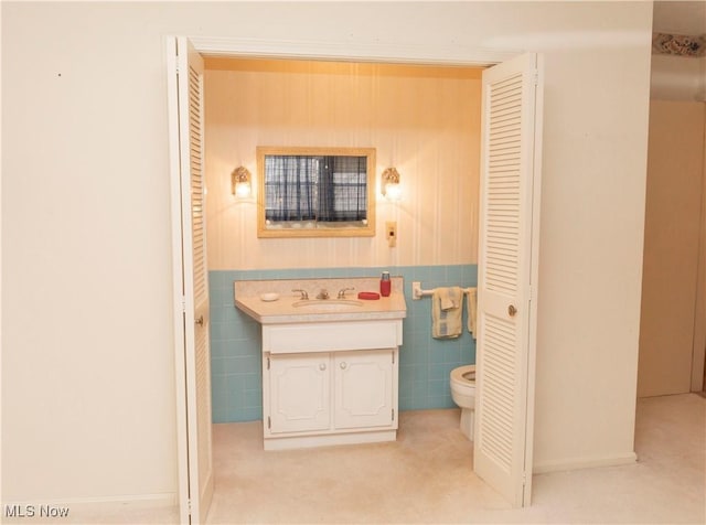 bathroom with vanity, tile walls, and toilet