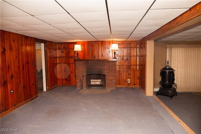 unfurnished living room with carpet flooring, a brick fireplace, and wood walls