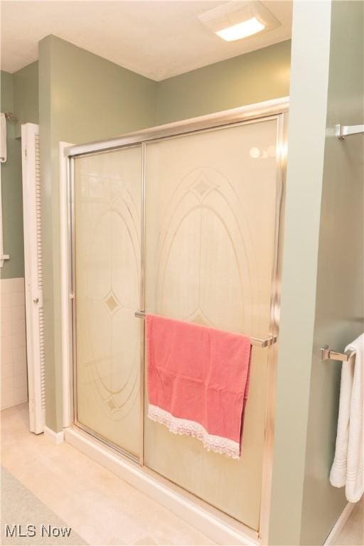 bathroom featuring a shower with shower door and tile walls