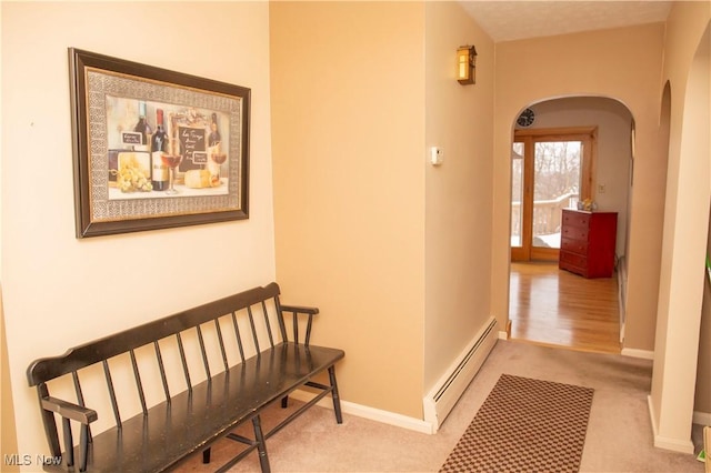 hallway with a baseboard radiator and light colored carpet