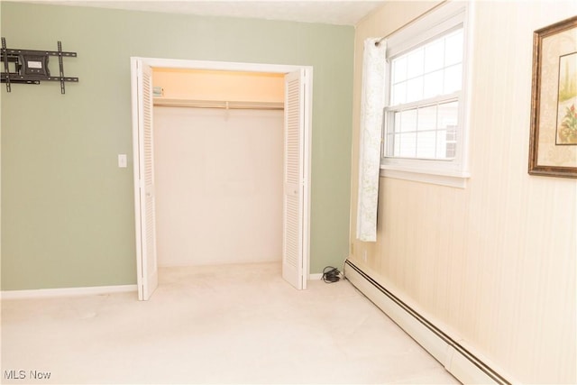 unfurnished bedroom with carpet, baseboard heating, and a closet