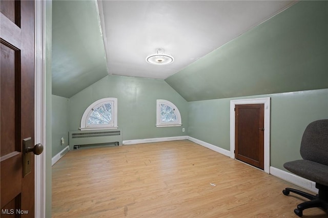 additional living space featuring radiator, lofted ceiling, and light hardwood / wood-style flooring