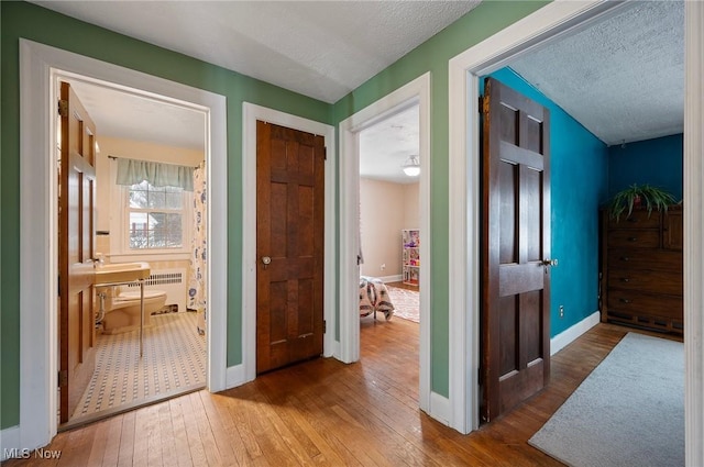 hall featuring a textured ceiling, radiator, and wood-type flooring