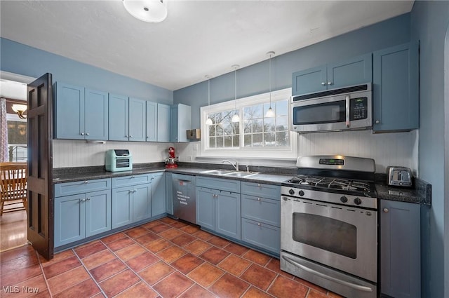 kitchen with stainless steel appliances, blue cabinetry, sink, hanging light fixtures, and dark tile patterned floors