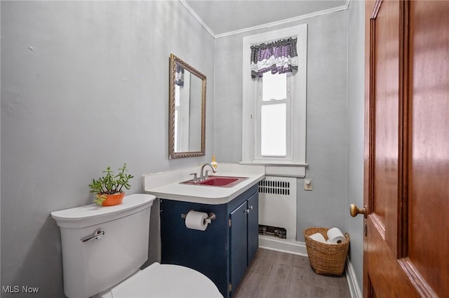 bathroom with radiator, vanity, toilet, hardwood / wood-style flooring, and crown molding