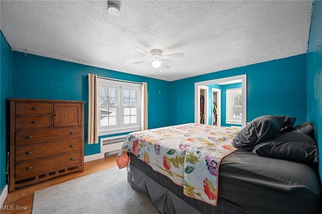 bedroom featuring ceiling fan, light hardwood / wood-style floors, a textured ceiling, and radiator