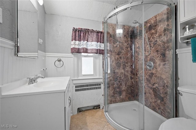 bathroom with radiator heating unit, tile patterned flooring, vanity, toilet, and walk in shower