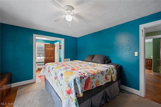 bedroom featuring ceiling fan, baseboard heating, a textured ceiling, and light hardwood / wood-style floors