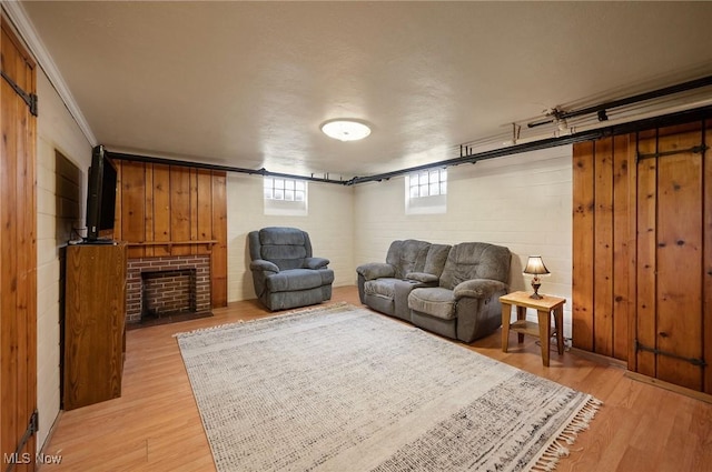 living room with ornamental molding, light hardwood / wood-style flooring, wood walls, and a fireplace