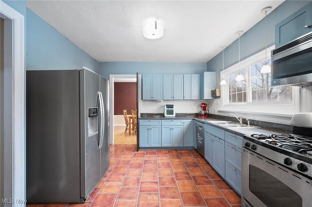 kitchen featuring sink, pendant lighting, appliances with stainless steel finishes, and blue cabinets