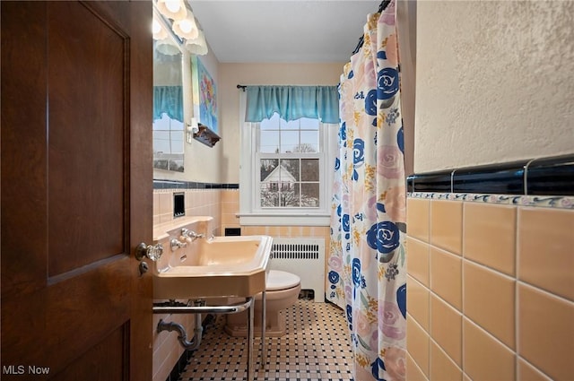 bathroom with tile walls, toilet, radiator heating unit, and a shower with curtain