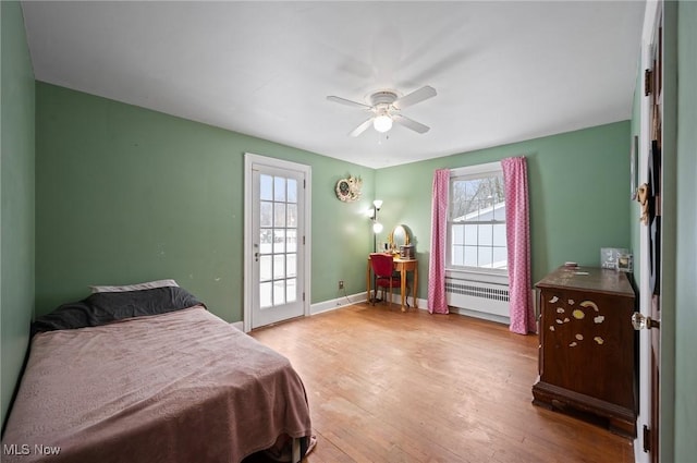 bedroom featuring radiator, ceiling fan, light hardwood / wood-style flooring, and multiple windows