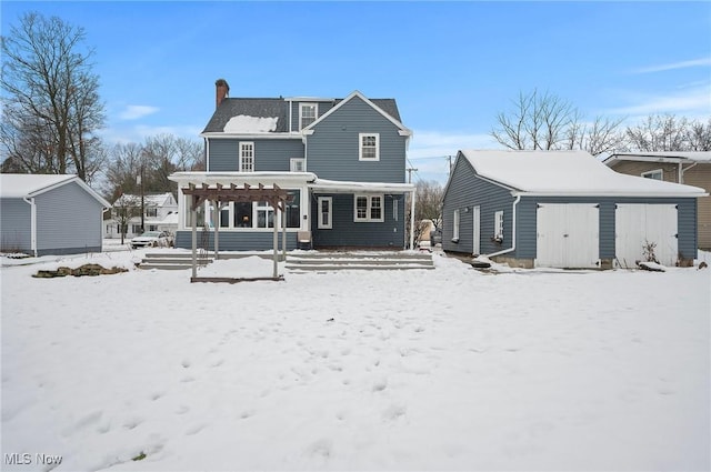 snow covered rear of property featuring a pergola and an outbuilding