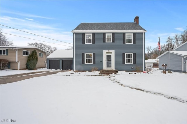 colonial inspired home with a garage and an outbuilding