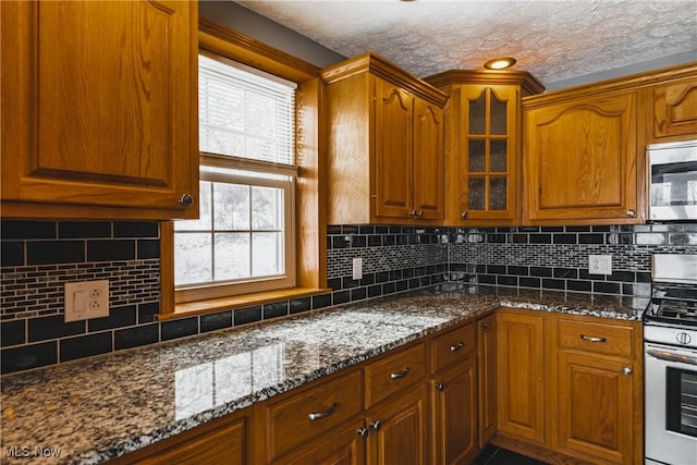 kitchen with dark stone countertops, tasteful backsplash, stainless steel appliances, and a textured ceiling