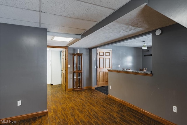 interior space featuring a drop ceiling and dark wood-type flooring