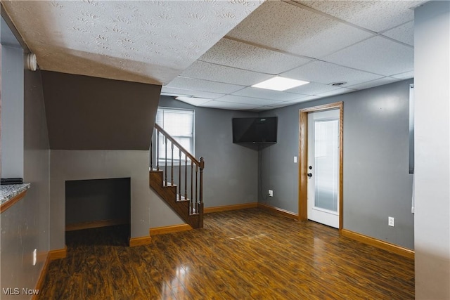 interior space featuring a paneled ceiling, dark hardwood / wood-style flooring, and a fireplace