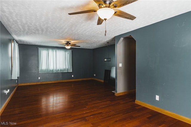 empty room with dark hardwood / wood-style flooring, ceiling fan, and a textured ceiling