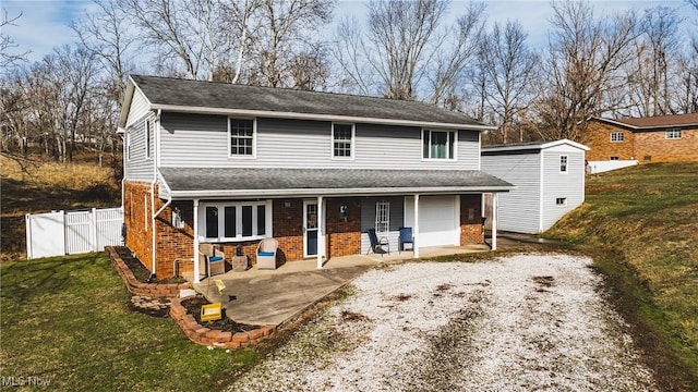 front facade with a storage shed, a patio, a front lawn, and a garage