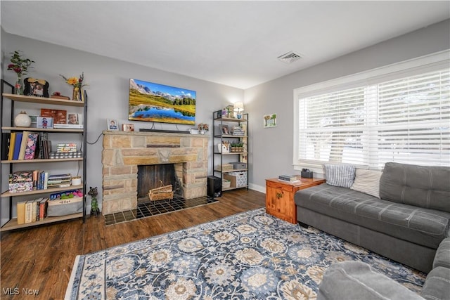 living room with dark hardwood / wood-style floors and a stone fireplace