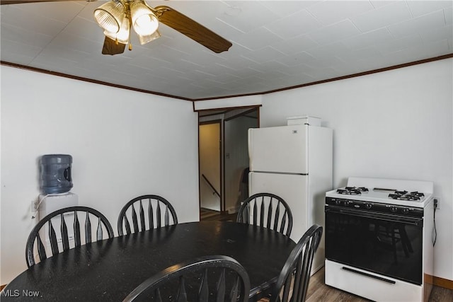 dining space featuring dark wood-type flooring, ornamental molding, and ceiling fan