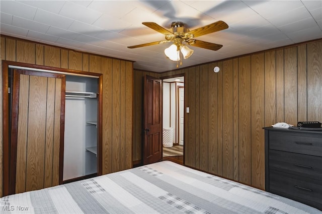 unfurnished bedroom featuring ceiling fan, a closet, and wooden walls