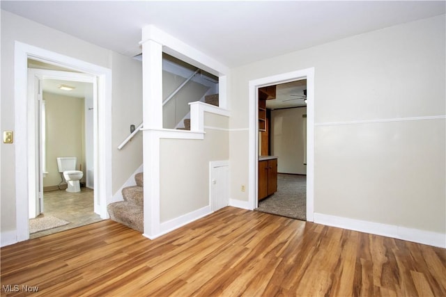 unfurnished room with stairway, baseboards, and light wood-style floors