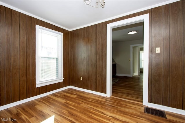 spare room featuring crown molding, hardwood / wood-style floors, and wooden walls