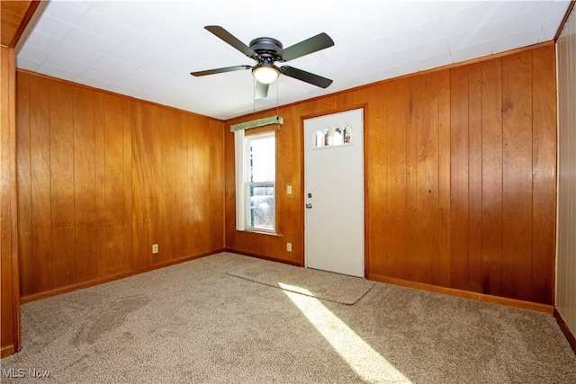 carpeted foyer featuring ceiling fan and wooden walls