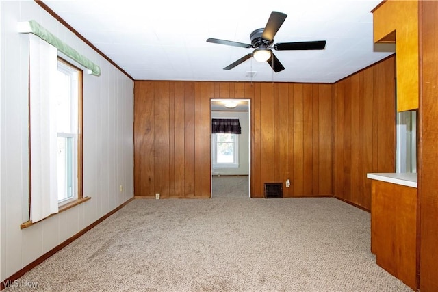 empty room with ceiling fan, light colored carpet, and wood walls