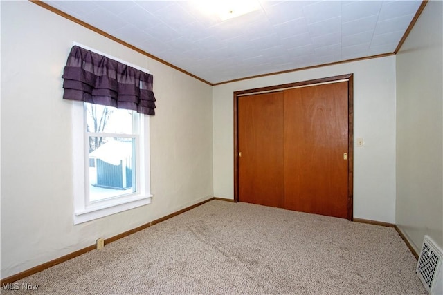 unfurnished bedroom with a closet, carpet, and crown molding