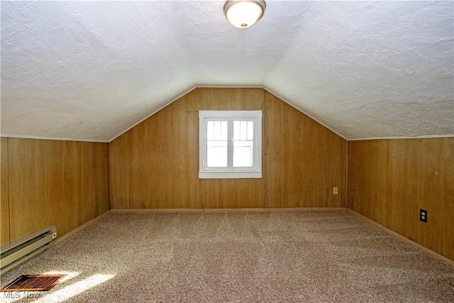 bonus room featuring a baseboard heating unit, a textured ceiling, vaulted ceiling, visible vents, and carpet floors