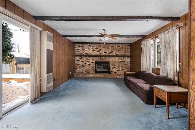 living room featuring beam ceiling, a wealth of natural light, wood walls, and a wood stove