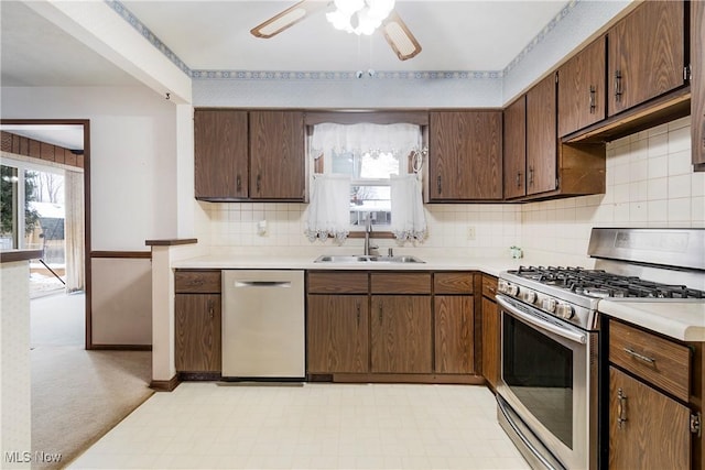 kitchen with light carpet, stainless steel appliances, sink, backsplash, and ceiling fan