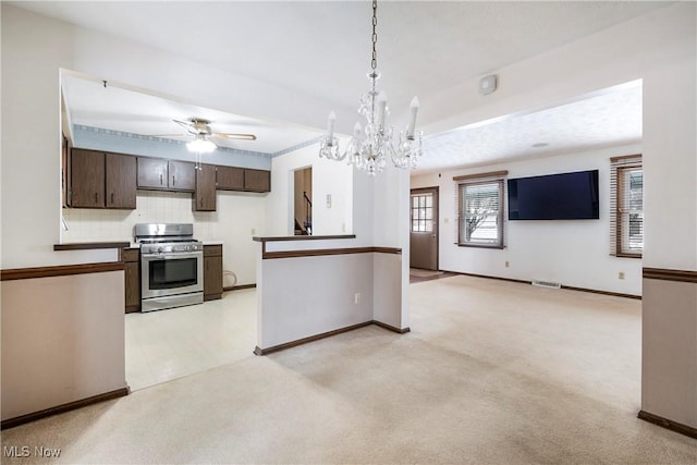 kitchen featuring stainless steel range with gas cooktop, dark brown cabinets, light colored carpet, a wealth of natural light, and pendant lighting