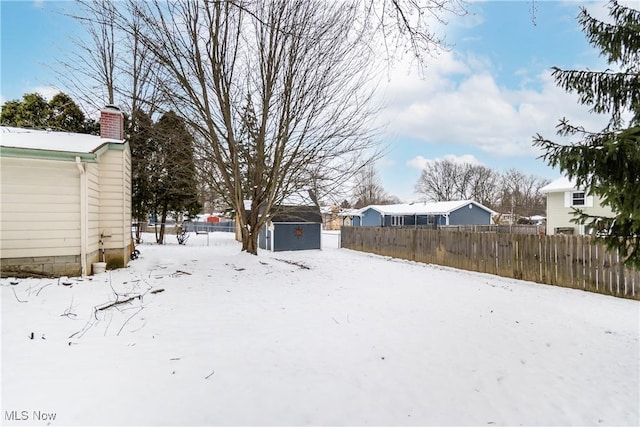 yard covered in snow featuring a storage shed