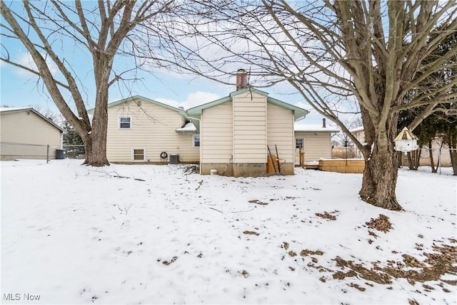 snow covered rear of property featuring cooling unit