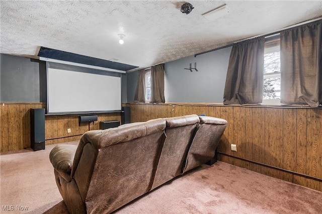 cinema room with carpet floors, wooden walls, and a textured ceiling