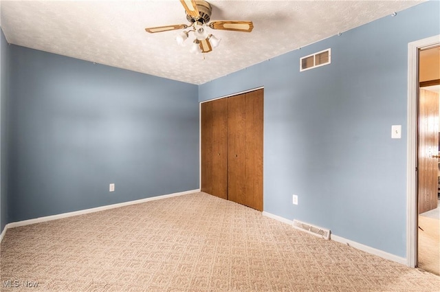 unfurnished bedroom featuring ceiling fan, a closet, carpet floors, and a textured ceiling