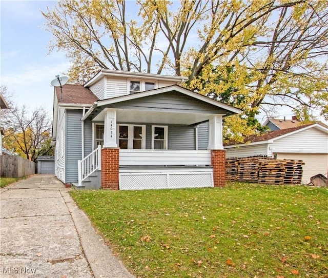 bungalow-style house with a front yard, a garage, and an outdoor structure