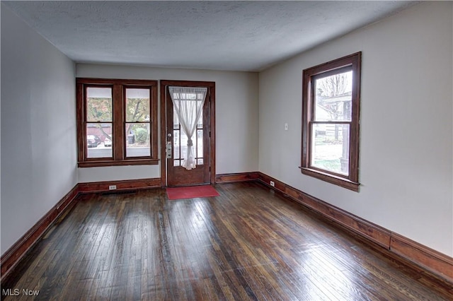 foyer entrance with a textured ceiling and dark hardwood / wood-style flooring