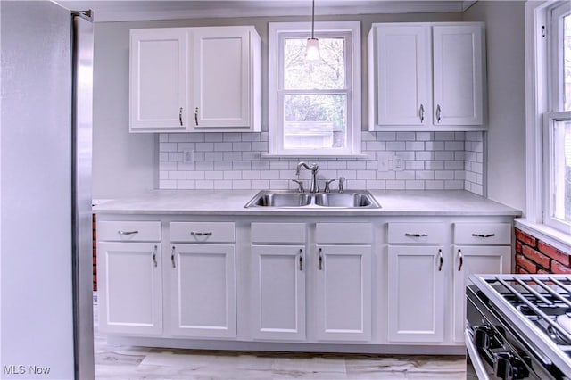 kitchen featuring hanging light fixtures, white cabinets, sink, and gas range