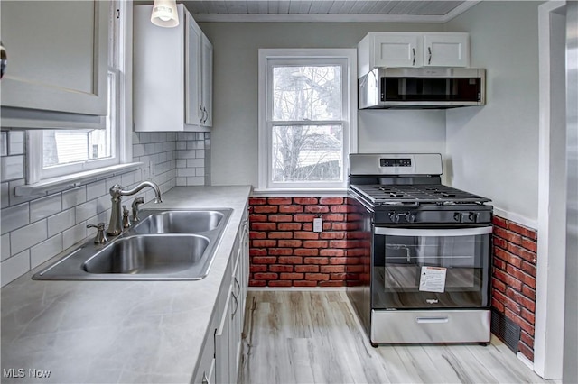 kitchen featuring appliances with stainless steel finishes, backsplash, white cabinets, light hardwood / wood-style flooring, and sink