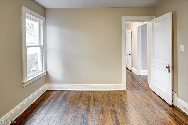 unfurnished room with dark wood-type flooring