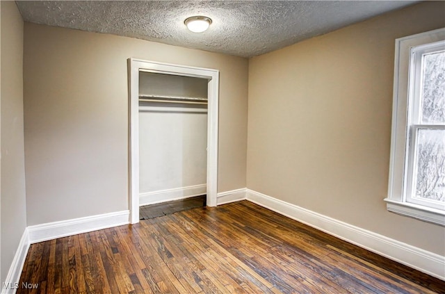 unfurnished bedroom with a textured ceiling, a closet, and dark hardwood / wood-style flooring